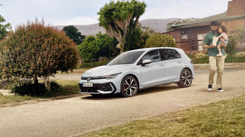 A man and a small child beside a Golf GTE