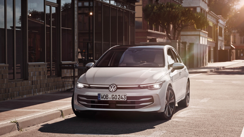 A white VW Golf parked next to a building in a sunny street