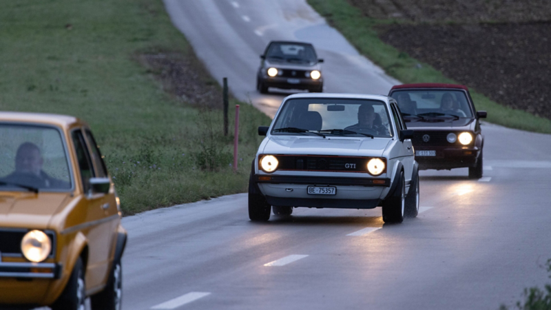 Mehrere alte Golf Modelle fahren hintereinander auf einer Strasse