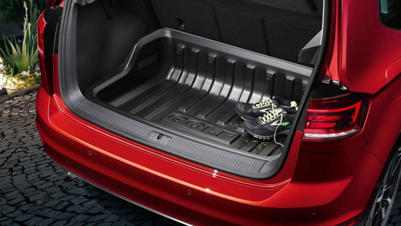 A father and his daughter look into the open luggage compartment of a VW car with a luggage compartment solution