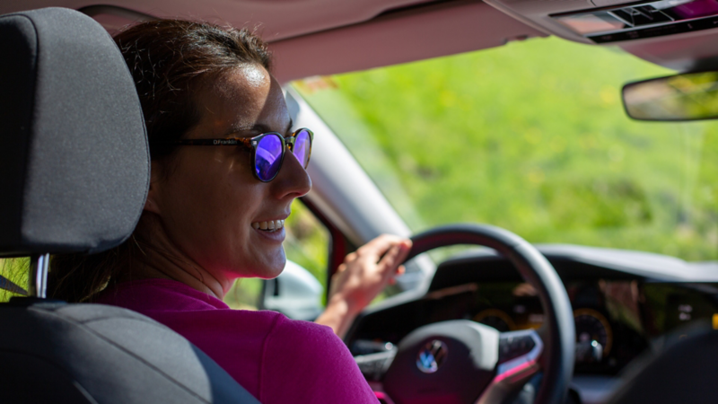Une femme portant des lunettes de soleil est assise au volant de la Golf Alltrack.