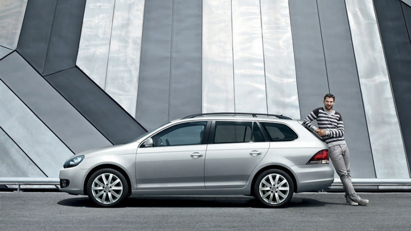 Side view of a silver Volkswagen Golf Estate with a man leaning on boot door