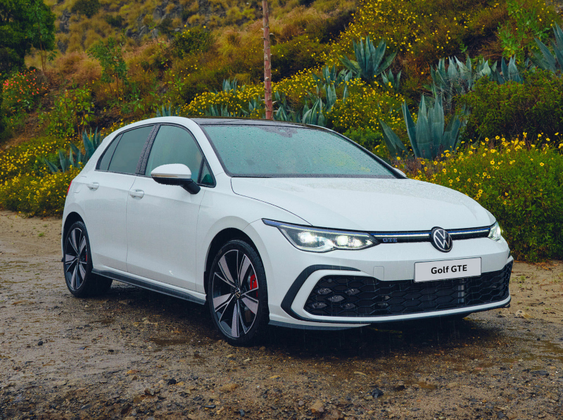 A white Golf GTE parked on a track next to some bushland 