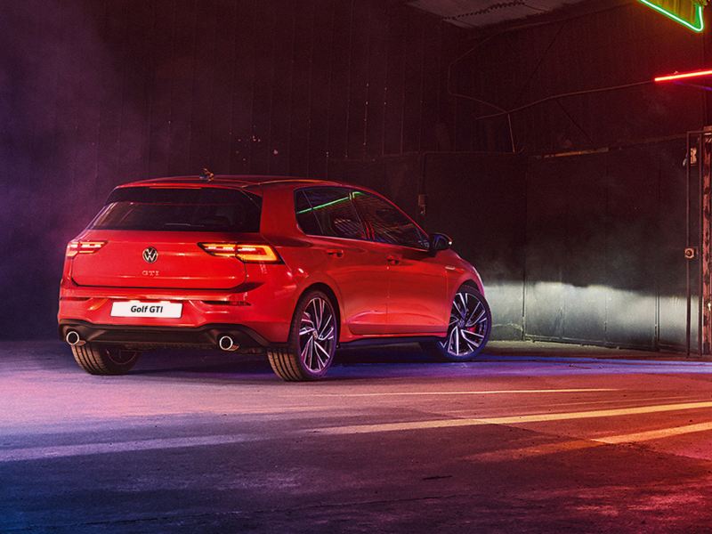 A red Volkswagen Golf GTI parked on a street with lighting