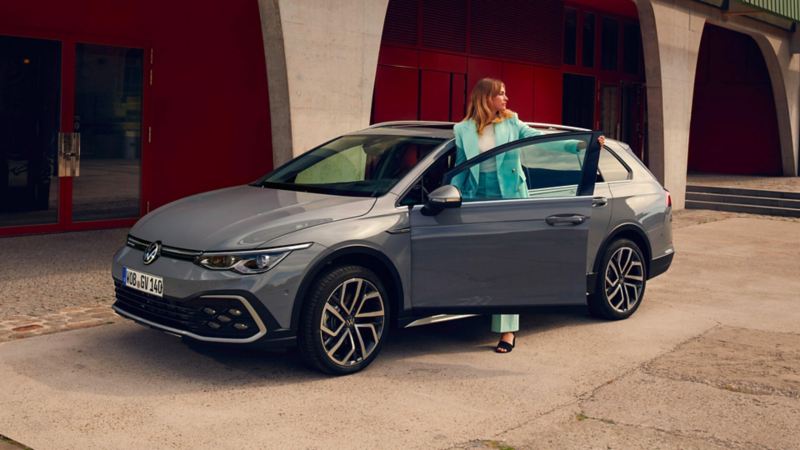 VW Golf SW Alltrack grise avec une femme qui entre par la porte conducteur