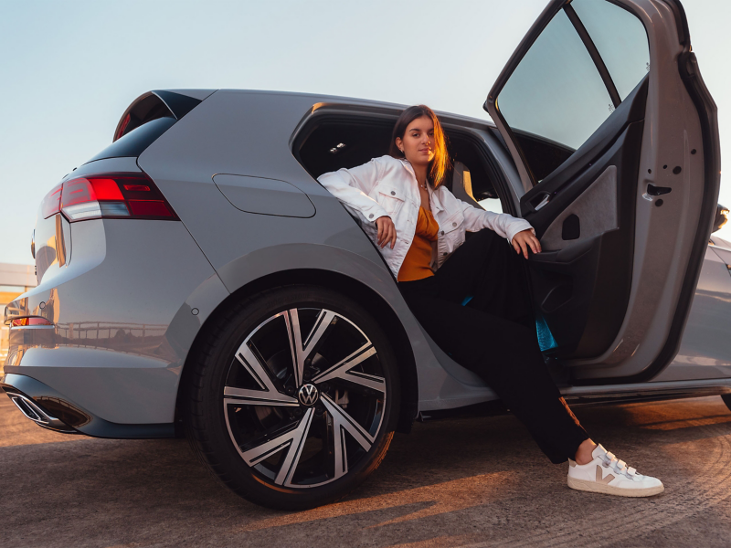 Woman on the back seat of the Volkswagen Golf R with door open.