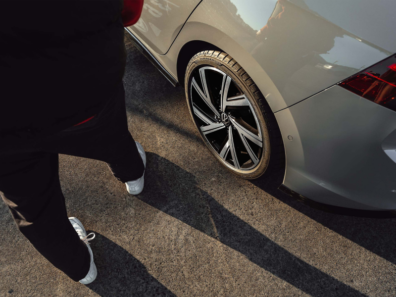 Man walking beside the Volkswagen Golf alloy wheel.