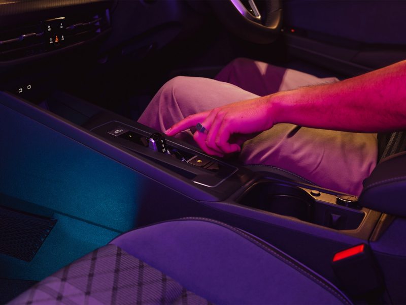 Close up of driver pushing automatic shifter in Volkswagen Golf.