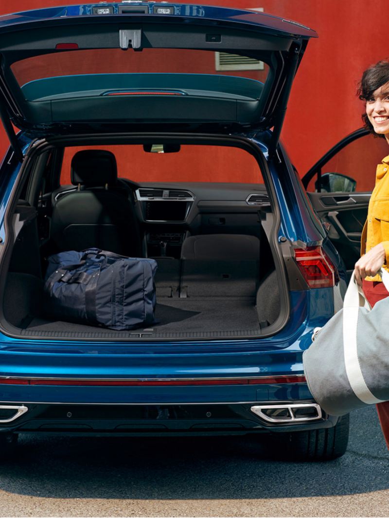Woman with sports bag on open tailgate of VW Tiguan