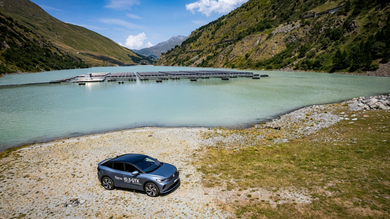 Des panneaux solaires sont visibles sur le lac des Toules et l'ID.5 GTX est paké au premier plan sur la rive du lac.