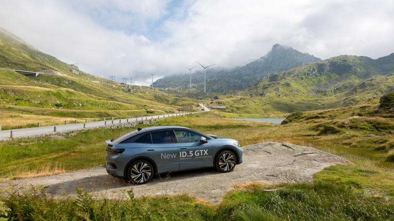 ID.5 GTX garé sur une petite place à côté de la route sur le col du Gothard et derrière le parc éolien du Gothard