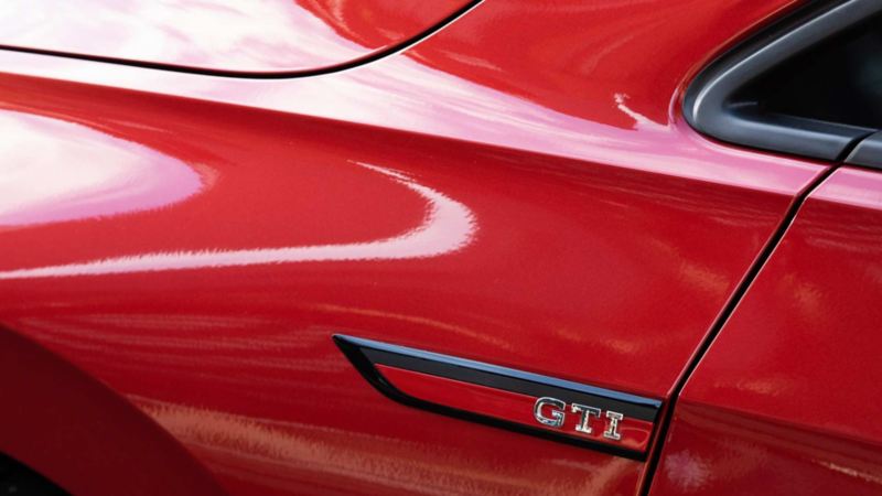 Emblema GTI en el exterior de modelo deportivo Volkswagen, en color rojo. 