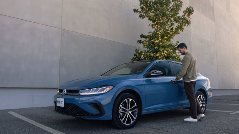 Conductor de auto sedán Volkswagen abre la puerta para ingresar.