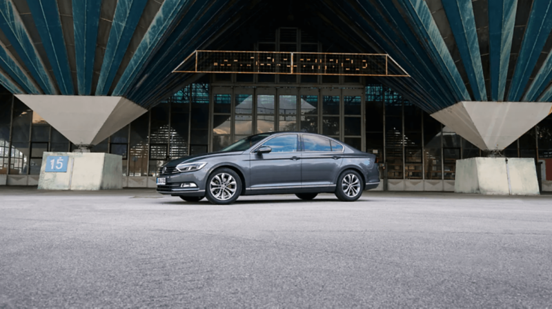 Szary Passat B8 stoi zaparkowany przed budynkiem