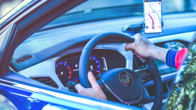 Hombre con manos sobre volante de auto Volkswagen equipado con sistemas de seguridad para evitar accidentes ji