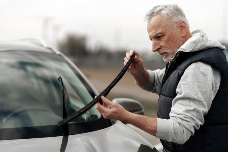 Persona limpiando un parabrisas de un coche