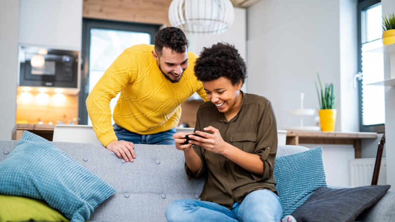 two people sitting at home looking at their phone