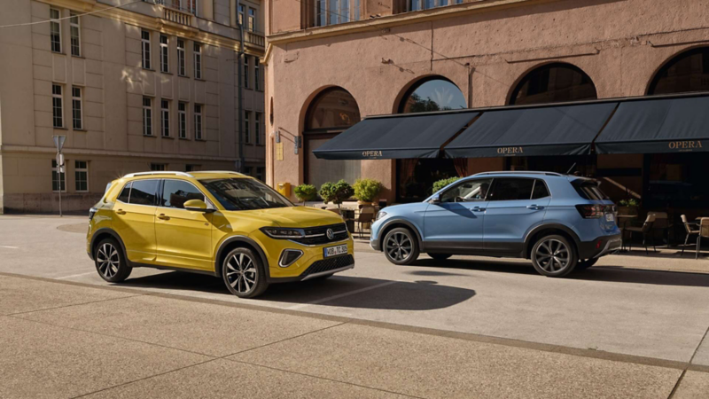 Un Volkswagen T-Cross amarillo y otro azul circulando en la ciudad