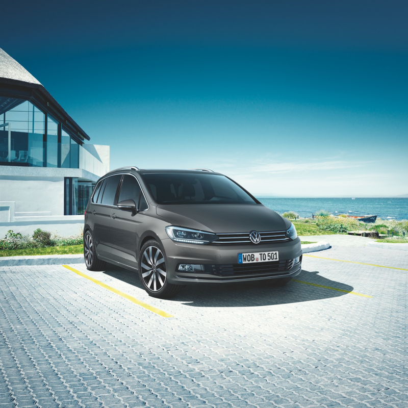 Un Volkswagen Touran de color gris estacionado fuera de una casa
