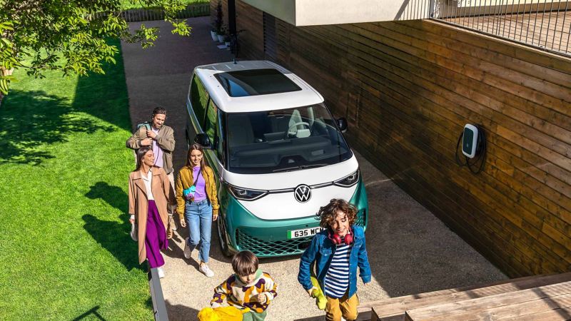 Photo of a family walking around an ID. Buzz parked next to a house. 