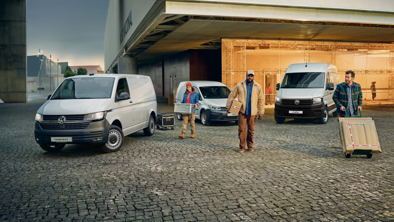 Volkswagen Commercial Vehicles parked outside modern building with people unloading luggage.