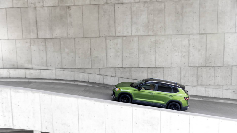 SUV Taos de Volkswagen en color verde sube una rampa de un edificio hecho de concreto.