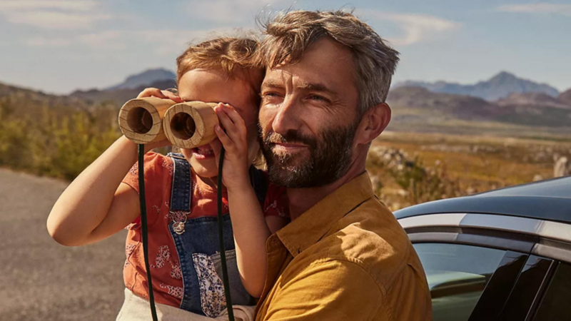 man holding child who is using binoculars 