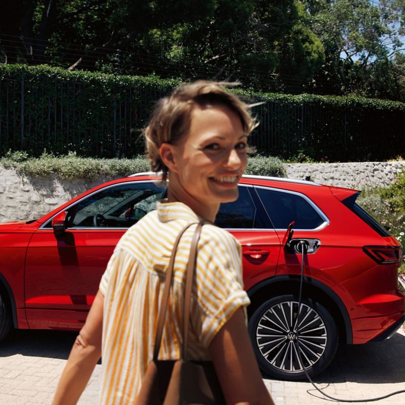 A woman looking at the camera whilst walking towards a VW Touareg