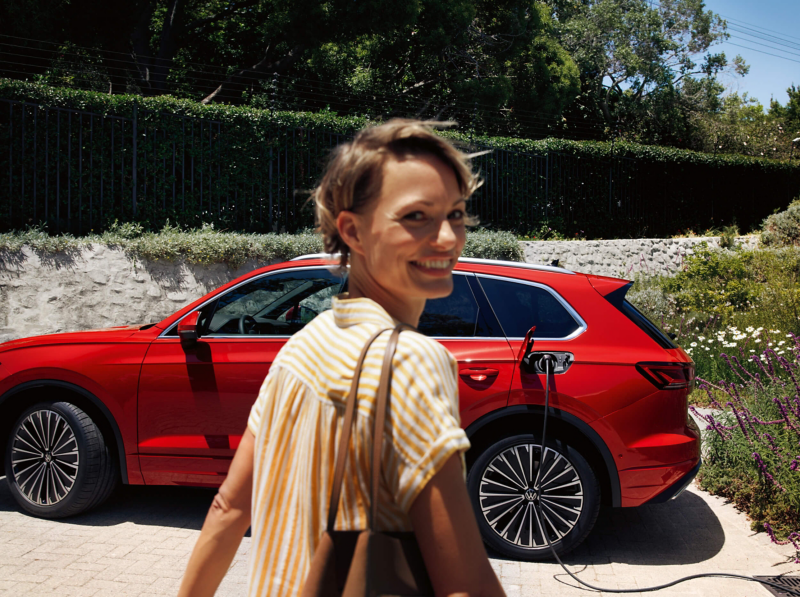 A woman looking at the camera whilst walking towards a VW Touareg