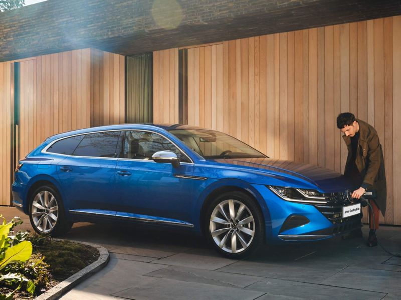 A man plugging a charger into an Arteon Shooting Brake car