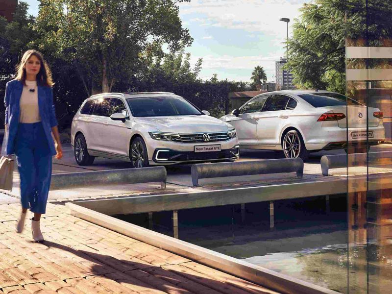 A woman walking near two Passat GTE cars