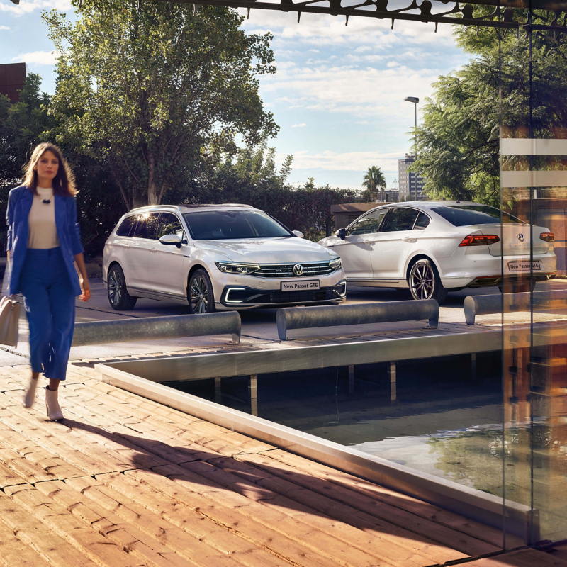 A woman walking near two Passat GTE cars