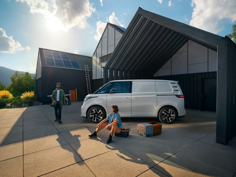 Mężczyzna i kobieta ze skrzynkami na narzędzia na tle białego Volkswagena ID. Buzz Cargo. 