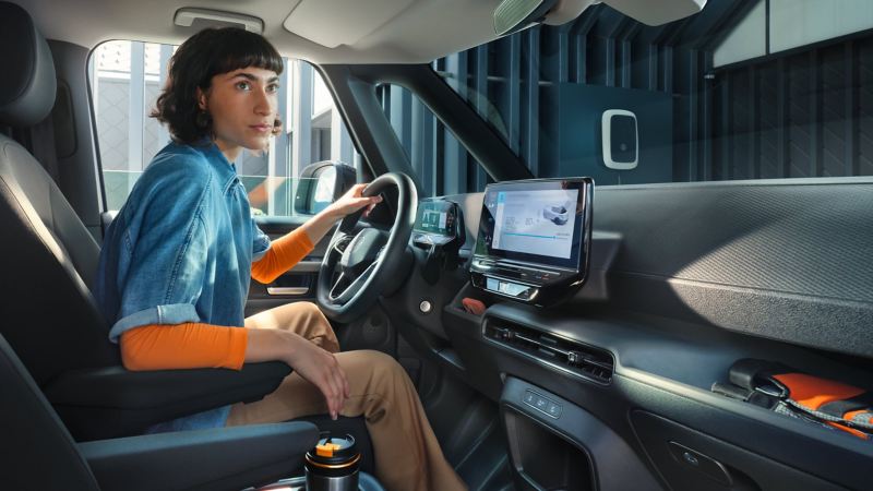 Eine Frau sitzt auf dem Fahrersitz des ID. Buzz Cargo und verbindet ihr Handy mit dem Fahrzeug.