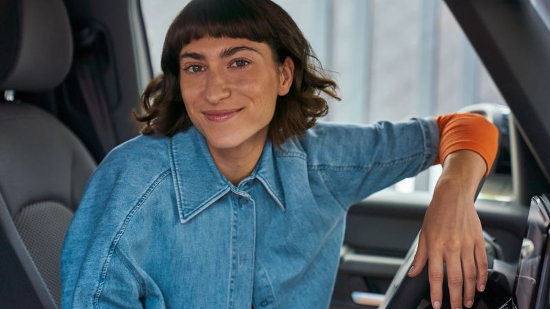 Eine Frau sitzt auf dem Fahrersitz eines VW Nutzfahrzeugs.