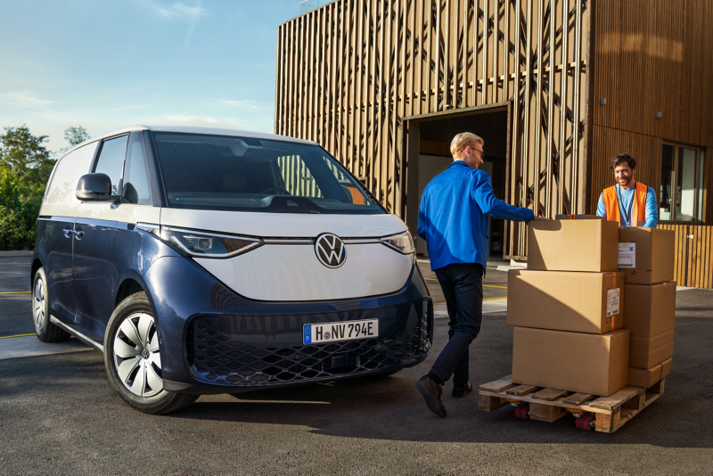 Ein Kurier liefert eine Palette Pakete mit dem VW ID. Buzz Cargo an einer Lagerhalle aus Holz ab