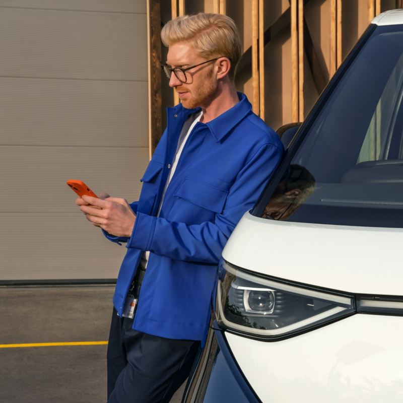 person leaning against a VW Van using a mobile