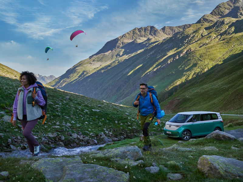 VW ID. Buzz parcheggiato vicino a un torrente in montagna.