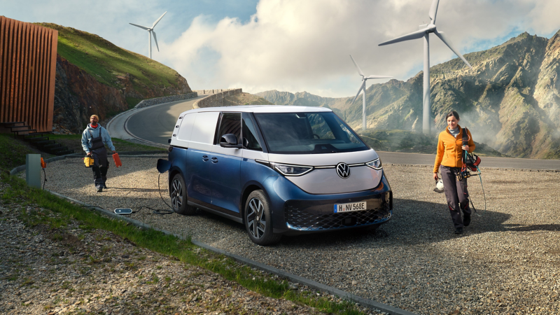 VW ID. Buzz Cargo parkt in den Bergen an Windturbinen.