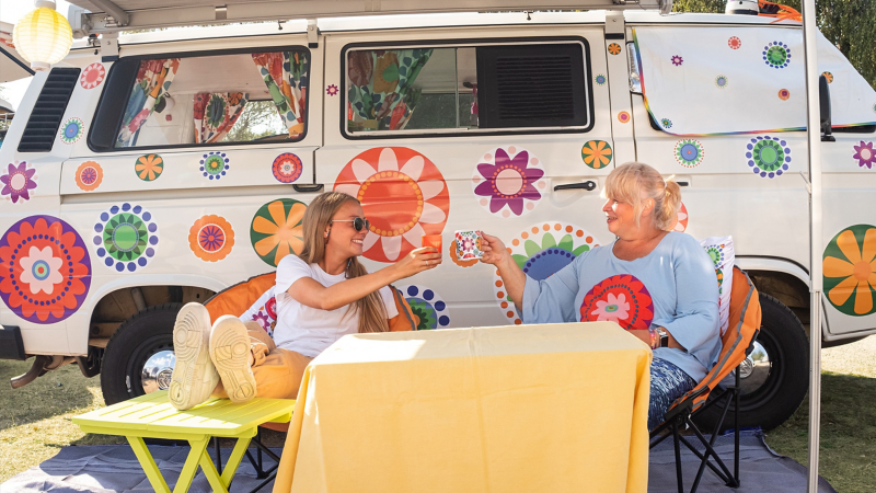 Due donne brindano sotto la tenda da sole del Volkswagen Bulli.