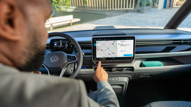 En man sitter i förarplatsen i en VW ID. Buzz och använder infotainmentsystemet
