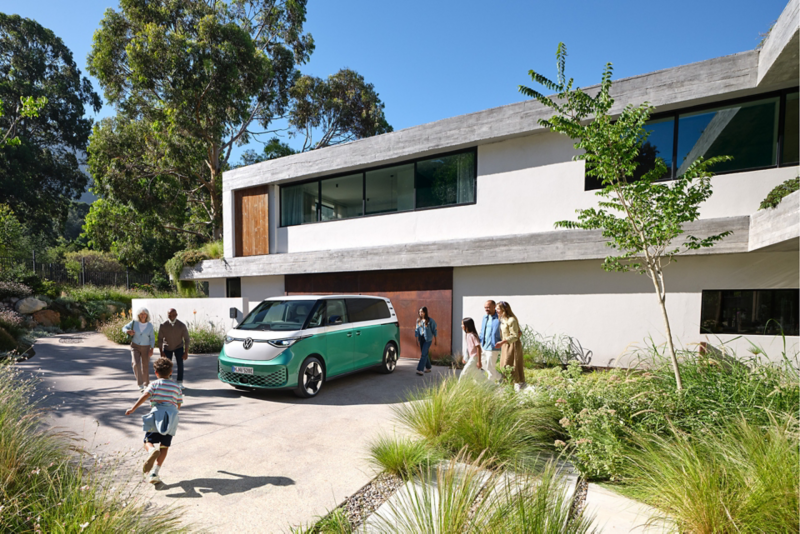 Volkswagen ID. Buzz blanc et vert devant une maison avec une famille