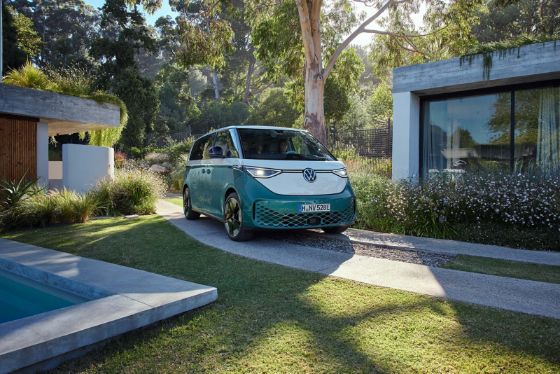 Ein VW ID. Buzz steht in der Einfahrt eines modernen Hauses.