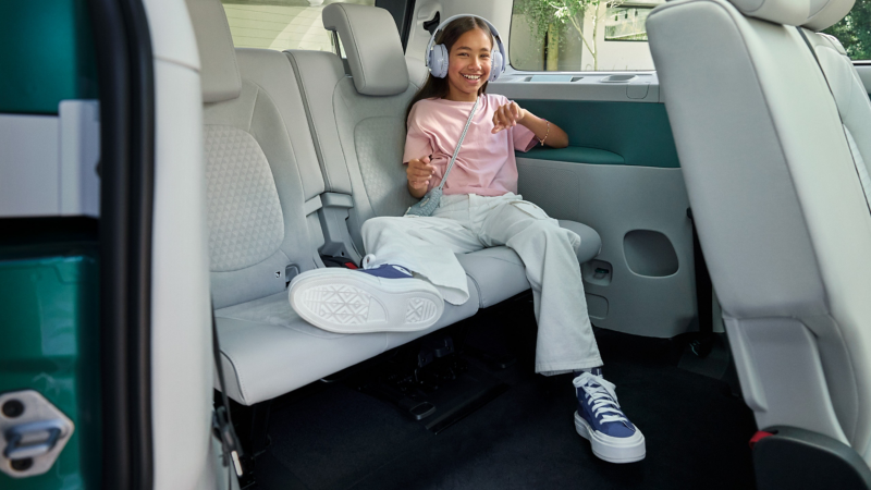 Ein junges Mädchen tobt auf der Rückbank des VW ID. Buzz.