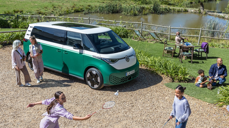 Familie beim Picknick neben einem VW ID. Buzz