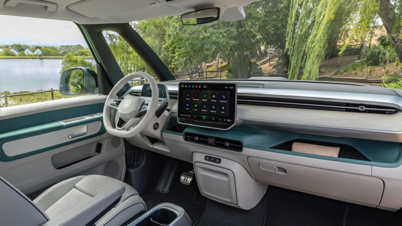 Un hombre apoyado en un VW ID. Buzz, mirando un móvil.