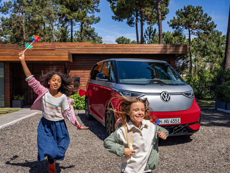 Ein VW ID. Buzz GTX 4MOTION parkt vor einem Gebäude. Im Vordergrund laufen Kinder auf der Auffahrt.