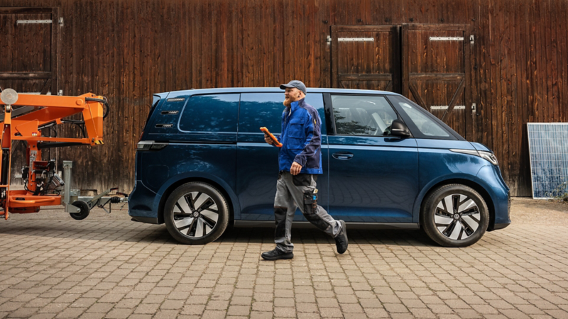 Monteur neben einem VW ID. Buzz Cargo mit angekoppeltem Anhänger.