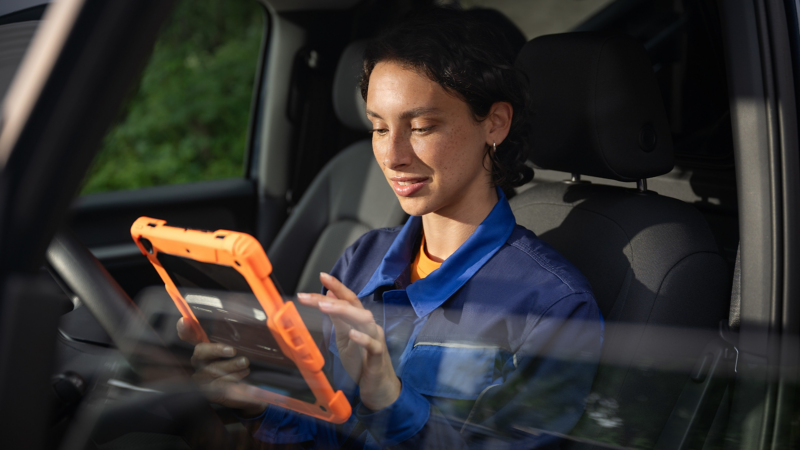 Eine Person sitzt in einen Volkswagen Nutzfahrzeug mit einem Tablet in der Hand.