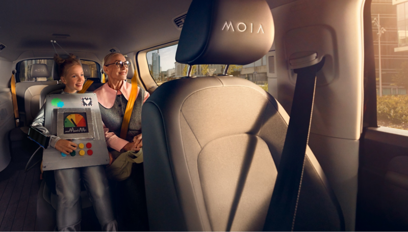 Ein Mädchen im Roboterkostüm und ihre Oma sitzen auf dem Rücksitz eines selbstfahrenden VW ID. Buzz.